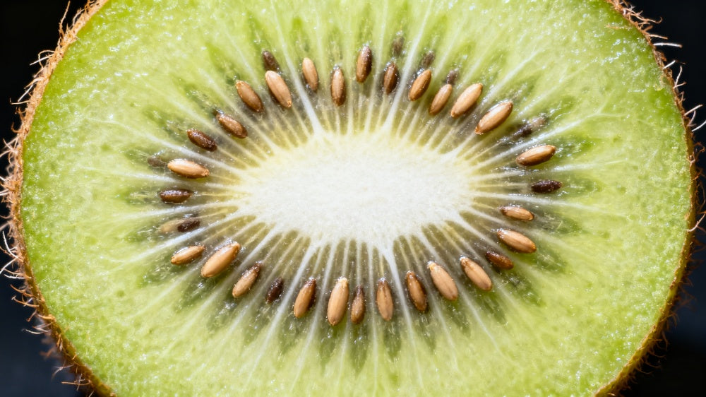 Close-up of a sliced kiwi fruit with seeds on a black background APEXEL TriScope 40X Shoot